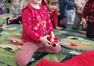 Dziewczynka z Żabek odkryła zabawkowy pojazd pod czerwonym materiałem.