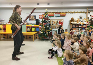 Pani Ania gra dzieciom melodię znanych piosenek świątecznych i kolęd na fagocie.