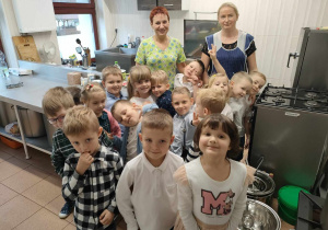 Poniedziałkowa wizyta dzieci z grupy "Pszczółek" w przedszkolnej kuchni. W tyłu są panie, które tam pracują - p. Barbara Skonieczko oraz p. Anna Jankowska.
