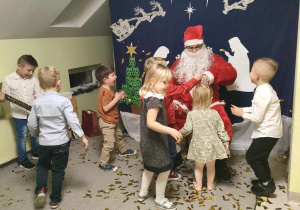 Kilkoro dzieci z grupy "Pszczółek" podczas zabawy ze Świętym Mikołajem.