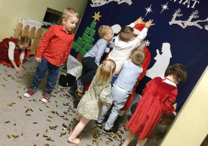 Kilkoro dzieci z grupy "Pszczółek" podczas zabawy ze Świętym Mikołajem.
