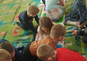 Dzieci z grupy "Biedronek" zapoznają się z kolorowymi płytkami sensorycznymi.