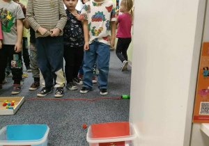 Zabawa ruchowa - "Rzuć kolor" - Artur ustawiony przed odpowiednim pojemnikiem rzuca piłką w kolorze pasującym do pojemnika. Pozostałe dzieci czekają na swoją kolej.