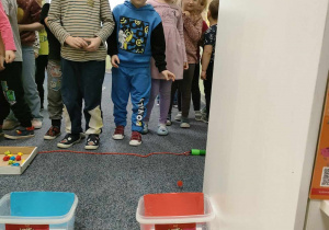 Zabawa ruchowa - "Rzuć kolor" - Wojtek ustawiony przed odpowiednim pojemnikiem rzuca piłką w kolorze pasującym do pojemnika. Pozostałe dzieci czekają na swoją kolej.
