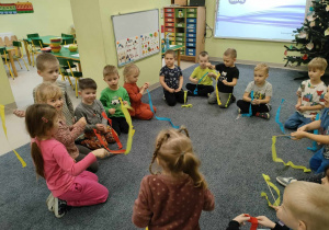 Dzieci podczas zabawy ruchowej "Namaluj w powietrzu", podczas której jedna osoba rusza wstążką w powietrzu a pozostałe dzieci naśladują ten ruch.