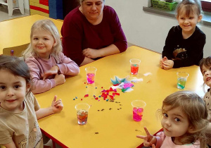 Kilkoro dzieci przy stoliku w trakcie tworzenia lodowych ozdób.