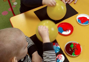 Dwoje dzieci przy stole podczas malowania balonami.