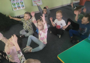 Dzieci siedzą przed tablicą interaktywną i biorą udział w ćwiczeniach wyciszających.