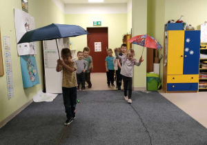 Artur i Oliwia podczas spaceru z parasolem po skakance.