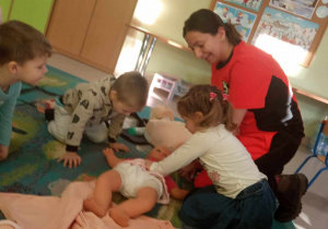 Mariczka z grupy "Żabek" ćwiczy udzielanie pierwszej pomocy na lalce.
