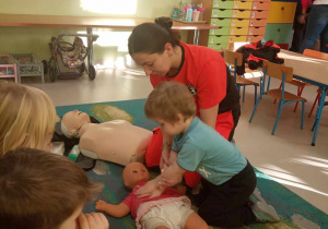 Bartuś z grupy "Żabek" ćwiczy udzielanie pierwszej pomocy na lalce.