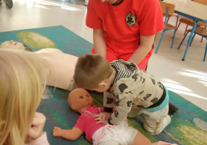 Bohdan z grupy "Żabek" ćwiczy udzielanie pierwszej pomocy na lalce.