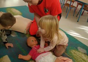 Lila z grupy "Żabek" ćwiczy udzielanie pierwszej pomocy na lalce.