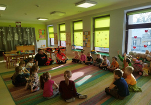 Dzieci z grupy "Skrzatów" siedzą na dywanie i rozmawiają z Prowadzącymi.