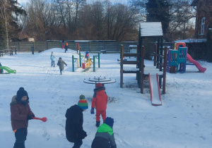 Zimowe zabawy "Biedronek" na ośnieżonym, przedszkolnym placu zabaw.