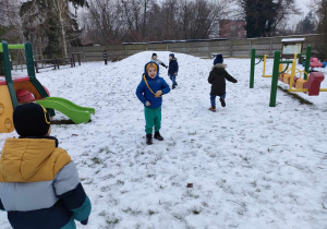 Zabawa w "berka" - Natan jest "berkiem" i goni pozostałe dzieci na przedszkolnym ogrodzie.