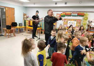 Pan Bogdan śpiewa i gra na gitarze, natomiast Pan Prowadzący rzuca do dzieci kapeluszem. Przedszkolaki bawią się i tańczą przy muzyce.