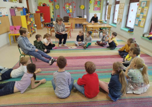 Pani Asia czyta bajkę pt. "Piękna i bestia" w grupie dzieci najstarszych - "Skrzatów". Dzieci siedzą w kole na dywanie.
