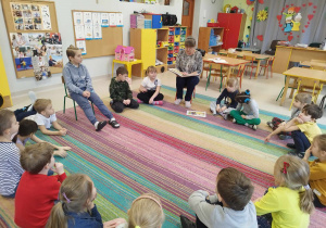 Pani Asia czyta bajkę pt. "Piękna i bestia" w grupie dzieci najstarszych - "Skrzatów". Dzieci siedzą w kole na dywanie.