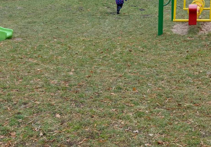 Kilkoro dzieci z grupy "Biedronek" biega po przedszkolnym placu zabaw.
