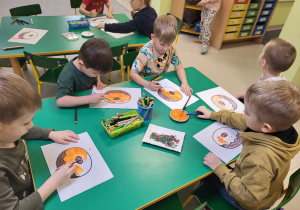 Kilkoro dzieci z "Pszczółek" maluje szablon pączka.