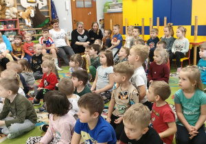 Dzieci siedzą na dywanie i słuchają p. Ewy Drzewieckiej.