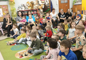 Dzieci siedzą na dywanie i słuchają p. Ewy Drzewieckiej.