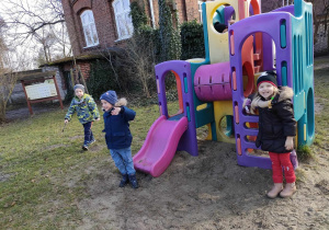 Filipek, Kajtuś i Karolinka przy konstrukcji na przedszkolnym placu zabaw.