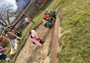 Zuzia, Filipek i Szymuś w piaskownicy na przedszkolnym placu zabaw.