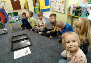 Dzieci siedzą w kole na dywanie i zastanawiają się, co to jest energia?