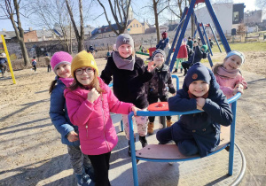 Kilkoro dzieci z grup: "Skrzatów" i "Biedronek" na karuzeli na placu zabaw w Parku Miejskim.