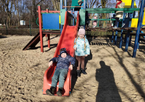 Dwoje dzieci z "Biedronek" na zjeżdżalni na placu zabaw w Parku Miejskim.