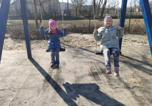 Antosia i Maja ze "Skrzatów" na huśtawkach na placu zabaw w Parku Miejskim.
