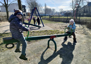 Dwoje dzieci z grupy "Biedronek" na konikach na placu zabaw w Parku Miejskim.