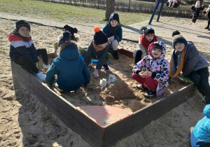Kilkoro dzieci z grup starszych w piaskownicy na placu zabaw w Parku Miejskim.