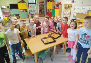 Dzieci pozują do zdjęcia z samodzielnie przygotowaną pizzą.