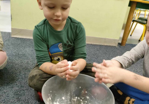 Filipek sprawdza konsystencję kulki, stworzonej z mąki ziemniaczanej i mydła do rąk.