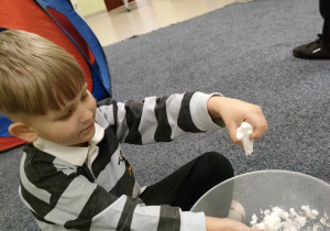 Arturek sprawdza konsystencję kulki, stworzonej z mąki ziemniaczanej i mydła do rąk.