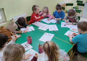 Dzieci siedzą przy stole i wykonują wybrane przez siebie zimowe karty pracy.