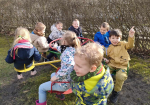 "Czas na aktywność ruchową na świeżym powietrzu" - dzieci bawią się swobodnie na karuzeli.