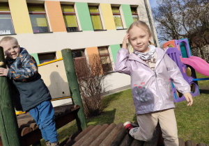 "Czas na aktywność ruchową na świeżym powietrzu" - Wojtuś i Marysia na konstrukcji na przedszkolnym placu zabaw.