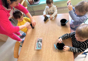 Kilkoro dzieci przy stoliczku podczas matematycznych zabaw ze spinaczami.