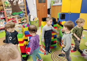 Kilkoro dzieci z grupy maluszków podczas zabawy z ogromnymi, kolorowymi klockami LEGO.