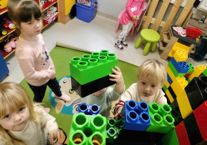 Kilkoro dzieci z grupy "Żabek" podczas zabawy z ogromnymi, kolorowymi klockami LEGO.