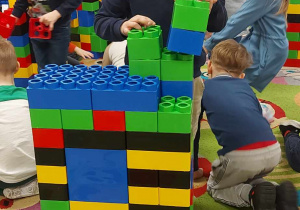 Kubuś S. z "Biedronek" buduje swoją konstrukcję z ogromnych, kolorowych klocków LEGO.