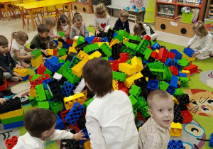 Dzieci z grupy "Motylków" podczas zabaw konstrukcyjnych z ogromnymi, kolorowymi klockami LEGO.