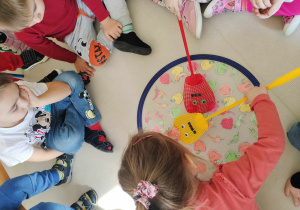 "Paprykowe wyzwanie". Dzieci próbują wyjąć z obręczy wybrany obrazek papryki, przy użyciu kolorowej łapki.