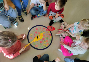 "Paprykowe wyzwanie". Dzieci próbują wyjąć z obręczy wybrany obrazek papryki, przy użyciu kolorowej łapki.
