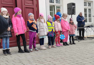 Amelia ze "Skrzatów" podczas prezentacji piosenki "Są takie święta...". Obok stoją dzieci z ozorkowskich przedszkoli oraz szkół.