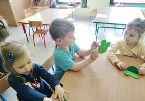 Kilkoro dzieci przy stoliczku podczas pracy plastycznej, opartej na stworzeniu żabki z kół origami.